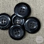 Szürke-fekete, négy lyukú kabátgomb